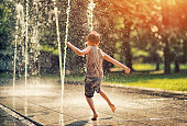Summer in the city - little boy playing with fountain