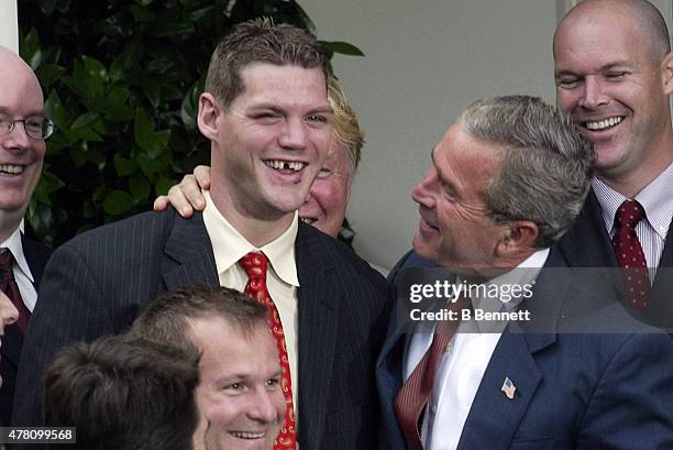 President George W. Bush puts his arm around NHL New Jersey Devils defenseman Colin White for a quick photo as unidentified members of the team look...