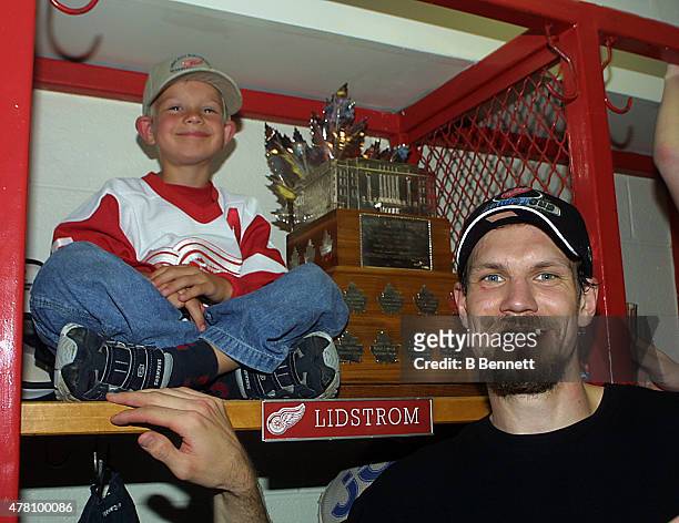 Niklas Lidstrom of the Detroit Red Wings celebrates a Stanley Cup victory with his son and the Conn Smythe Trophy on June 14, 2002 at the Joe Louis...