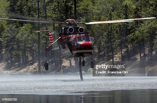 Firefighting helicopter sucks up water from Jenks Lake, as it works to control flames in the Lake Fire, in the San Bernardino National Forest near...