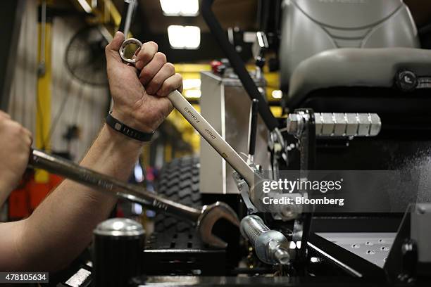 Worker tightens a bolt on a completed lawnmower at the Dixie Chopper manufacturing facility in Coatesville, Indiana, U.S., on Friday, June 12, 2015....