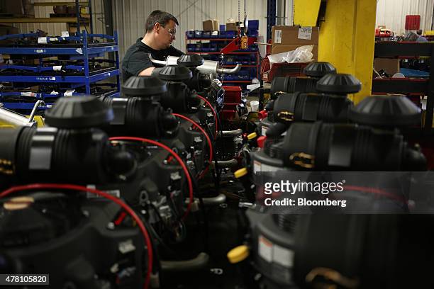 Worker prepares Kawasaki brand engines for installation inside lawnmowers on the assembly line at the Dixie Chopper manufacturing facility in...