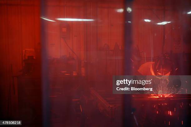 Worker welds a lawnmower frame together behind a plastic curtain on the assembly line at the Dixie Chopper manufacturing facility in Coatesville,...