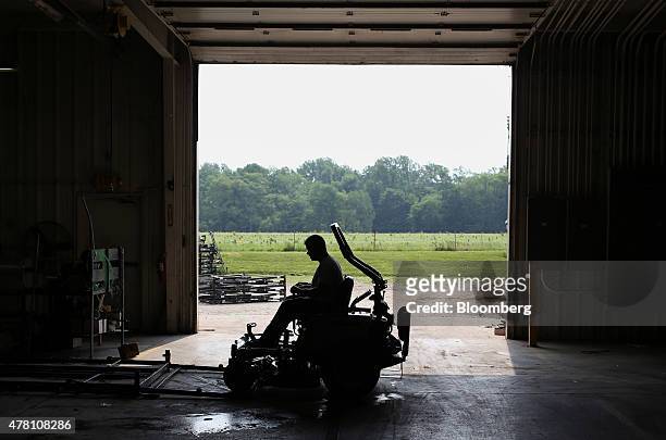 The silhouette of a worker is seen driving a completed Dixie Chopper lawnmower onto a shipping frame at the Dixie Chopper manufacturing facility in...