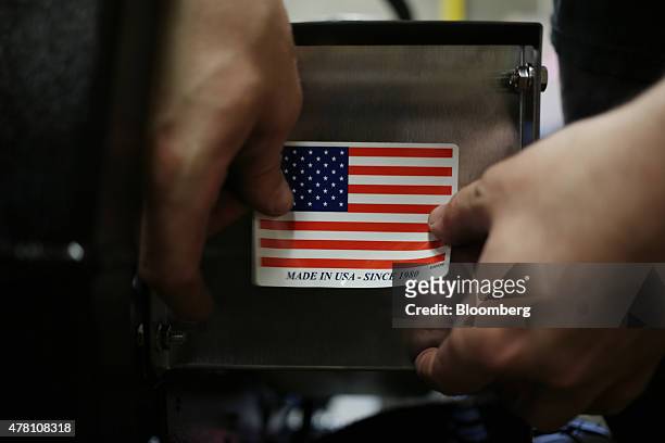 Worker puts a "Made in the USA" sticker on the back of a completed lawnmower at the Dixie Chopper manufacturing facility in Coatesville, Indiana,...