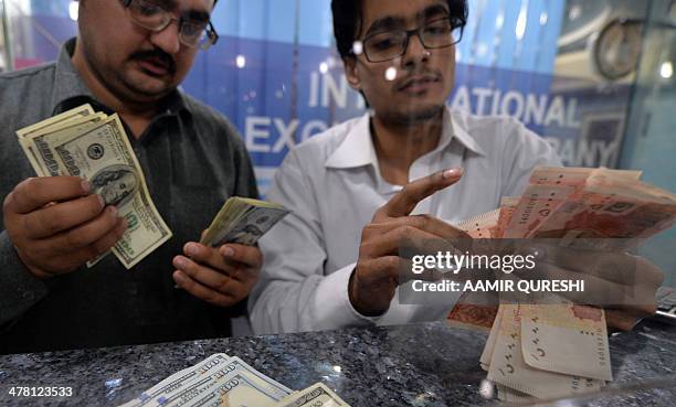 Money dealers counts Pakistani rupees and US dollars at a currency exchange in Islamabad on March 12, 2014. Pakistan's finance minister Ishaq Dar on...