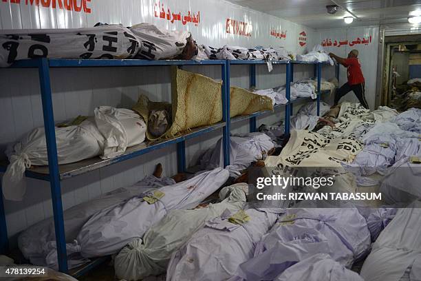 Pakistani volunteer checks identification paper of a heatstroke victim at a cold storage of the Edhi morgue in Karachi on June 23, 2015. The death...