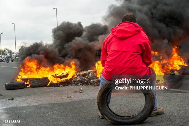 Striking employee of the French company My Ferry Link, a cross-channel ferry service, sits on a tyre in front of tyres set on fire as he takes part...