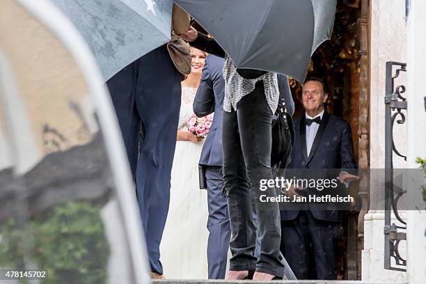 Monica Ivancan is shielded against the media and the rain with umbrellas as she leaves the church zum Hl. Kreuz after her wedding with Christian...