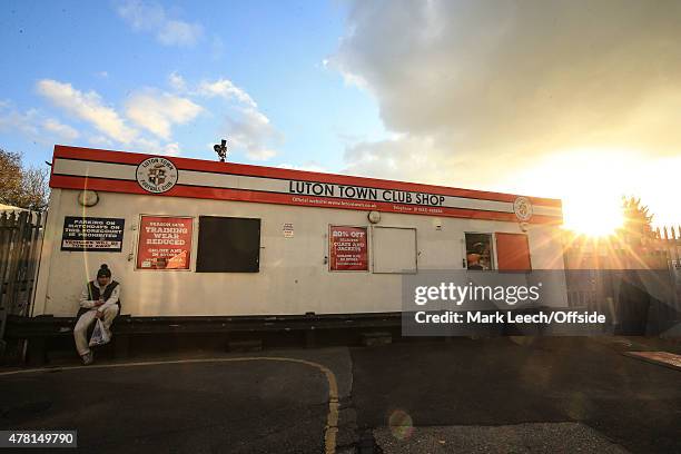 Man sits outside the Luton Town Club shop, waiting for it to open as the sun sets at Kenilworth Road during the Sky Bet League Two match between...