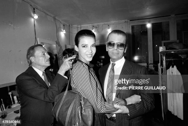 German fashion designer Karl Lagerfeld poses on January 24, 1983 with a model as French hairdresser Alexandre de Paris prepares her backstage ahead...
