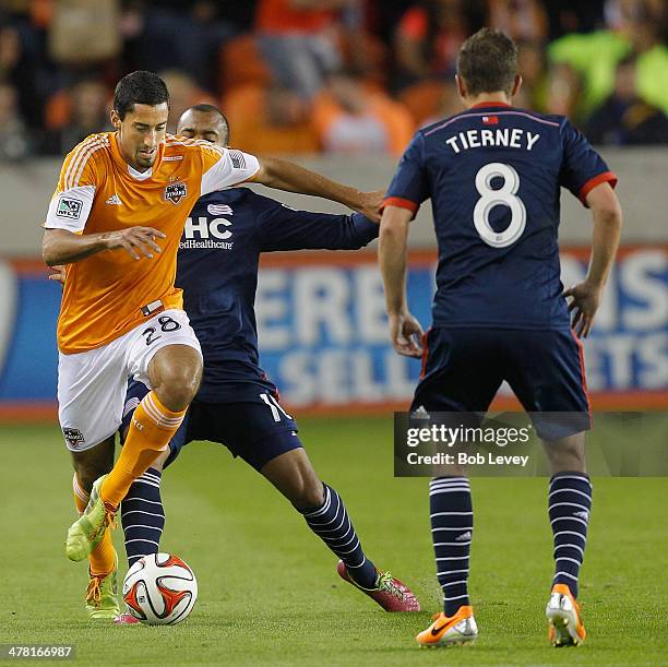 Tony Cascio of Houston Dynamo looks to get around Teal Bunbury of New England Revolution and Chris Tierney at BBVA Compass Stadium on March 8, 2014...