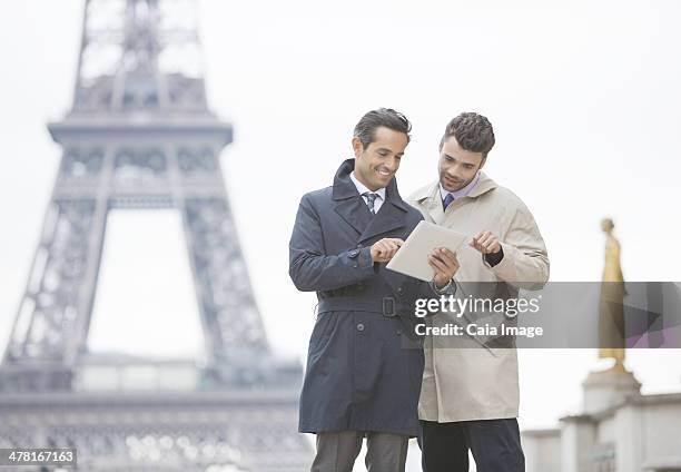 businessmen using digital tablet near eiffel tower, paris, france - france 2 stock pictures, royalty-free photos & images