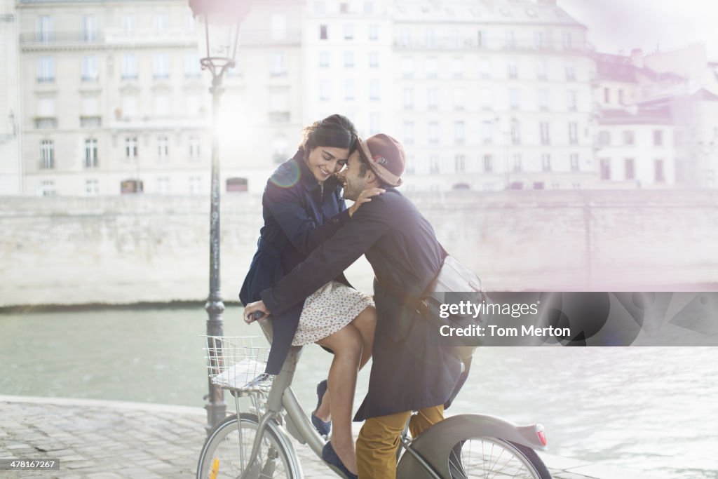 Couple hugging on bicycle along Seine River, Paris, France