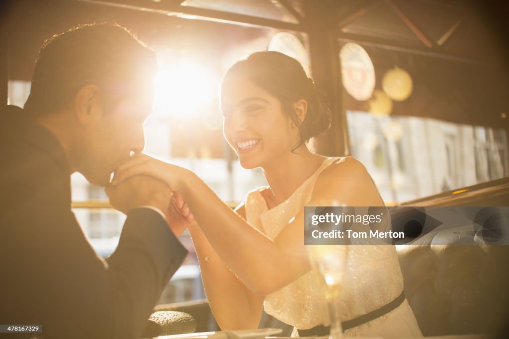 Man kissing girlfriend's hand in restaurant