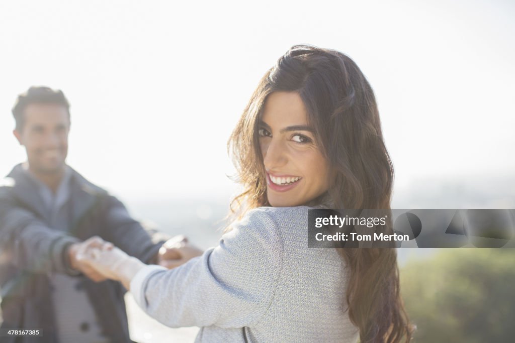 Couple holding hands with arms outstretched outdoors