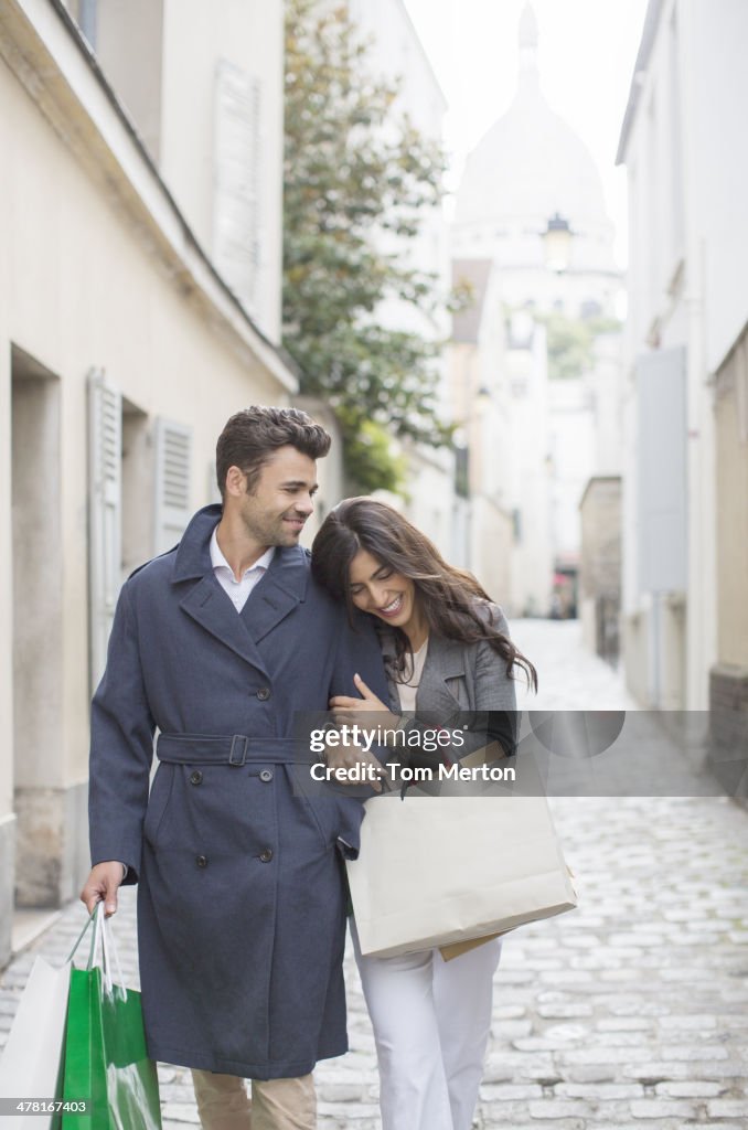 Couple transportant des sacs de shopping dans la rue pavée
