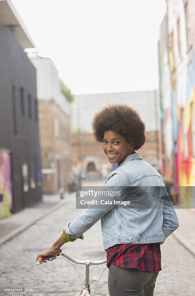 Woman pushing bicycle on city street