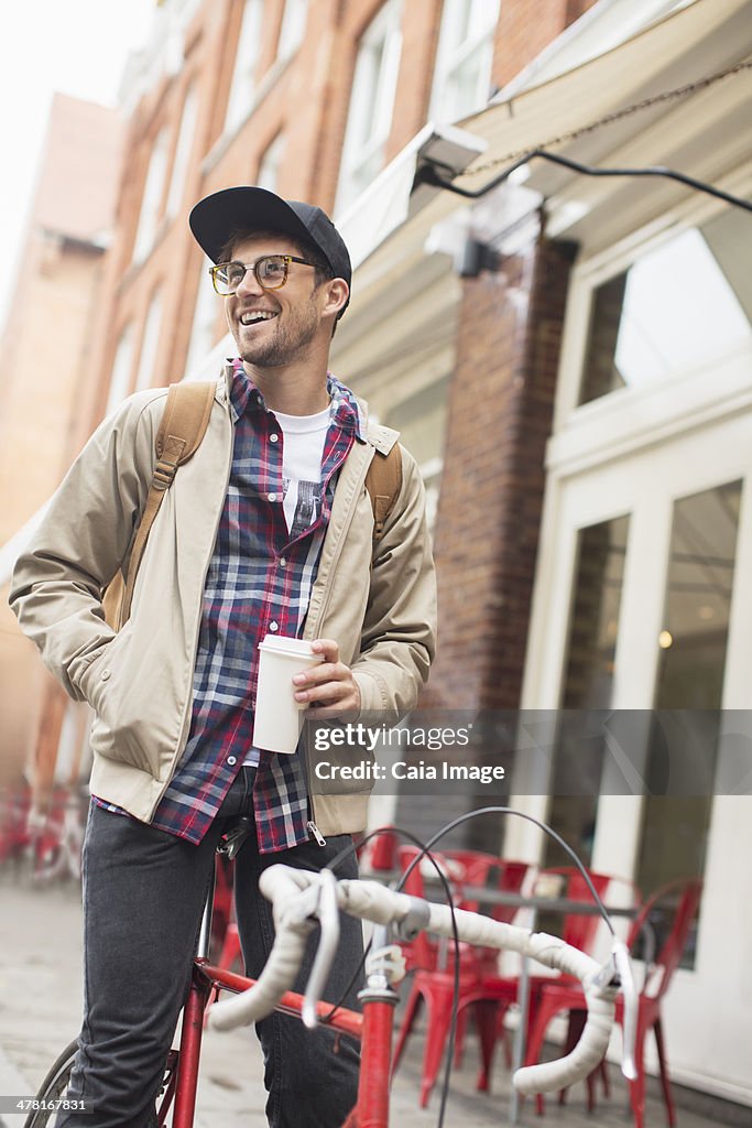 Man drinking coffee on bicycle on city street