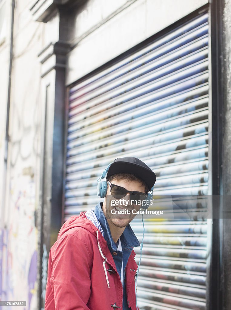 Man listening to headphones near graffiti wall