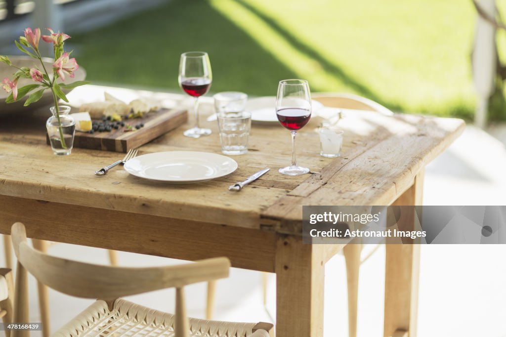 Wine and appetizer on wooden dining table on patio