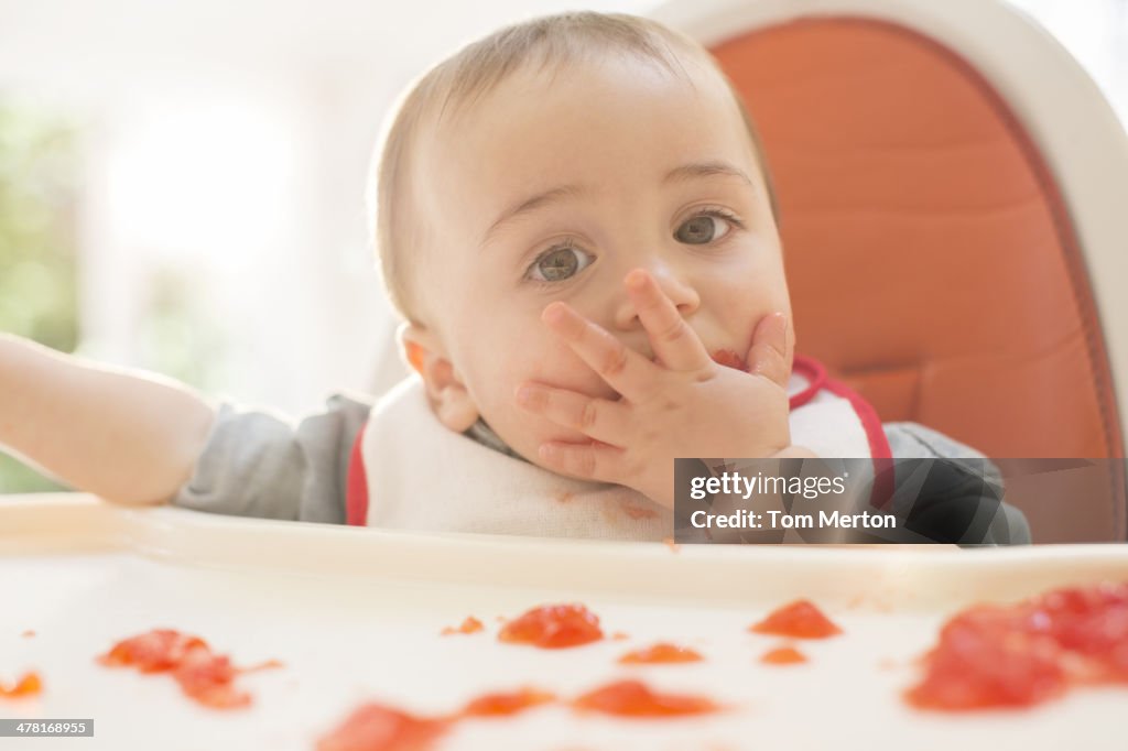 Baby boy eating gelatin dessert in high chair