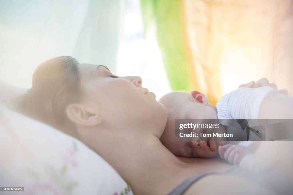 Mother and baby girl sleeping on bed
