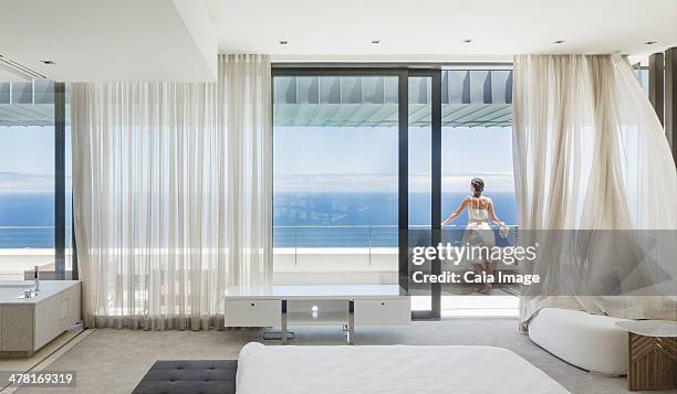 woman on modern balcony overlooking ocean - waterfront house stock pictures, royalty-free photos & images