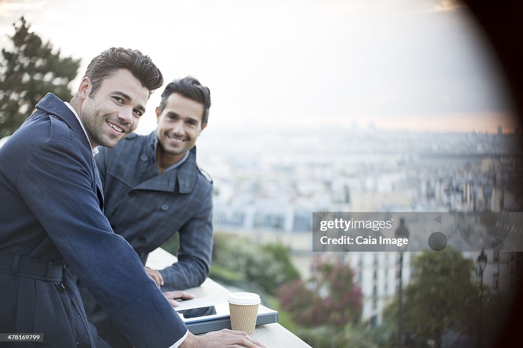 Businessmen smiling at railing overlooking Paris, France