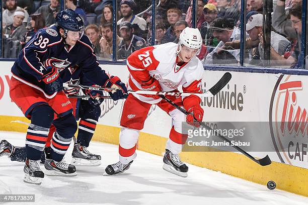 Boone Jenner of the Columbus Blue Jackets and Cory Emmerton of the Detroit Red Wings battle for control of the puck on March 11, 2014 at Nationwide...
