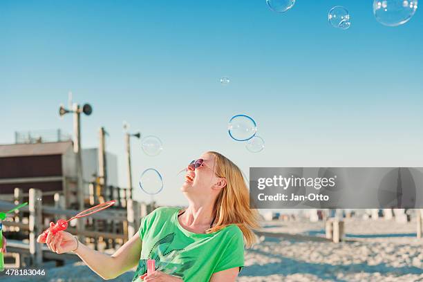 blonde girl making some soapbubbles on the beach of st.peter-ording - st peter ording stock pictures, royalty-free photos & images