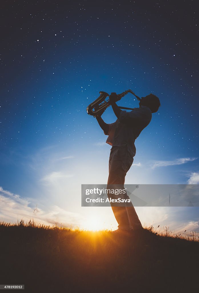 Saxophonist playing at sunset