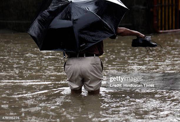 Man wade through a flooded street after heavy rain at Hindamata, Dadar on June 23, 2015 in Mumbai, India. Heavy rainfall across Mumbai city and...