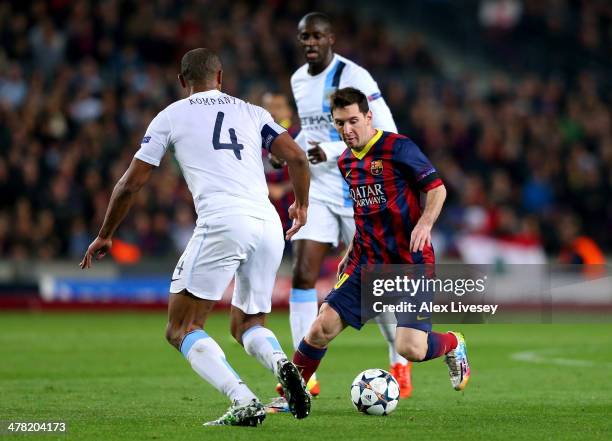 Lionel Messi of Barcelona is challenged by Vincent Kompany of Manchester City during the UEFA Champions League Round of 16, second leg match between...