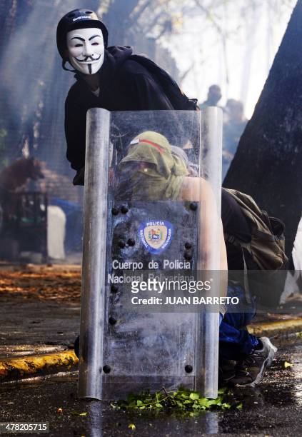 Venezuelan students protect themselves with a shield of riot policemen during a protest against the government of President Nicolas Maduro, in...