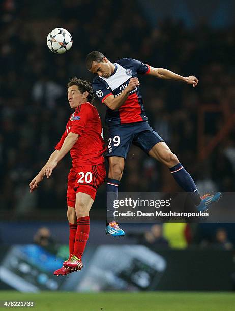 Lucas Moura of Paris Saint-Germain jumps with Andres Guardado of Bayer Leverkusen during the UEFA Champions League Round of 16 second leg match...