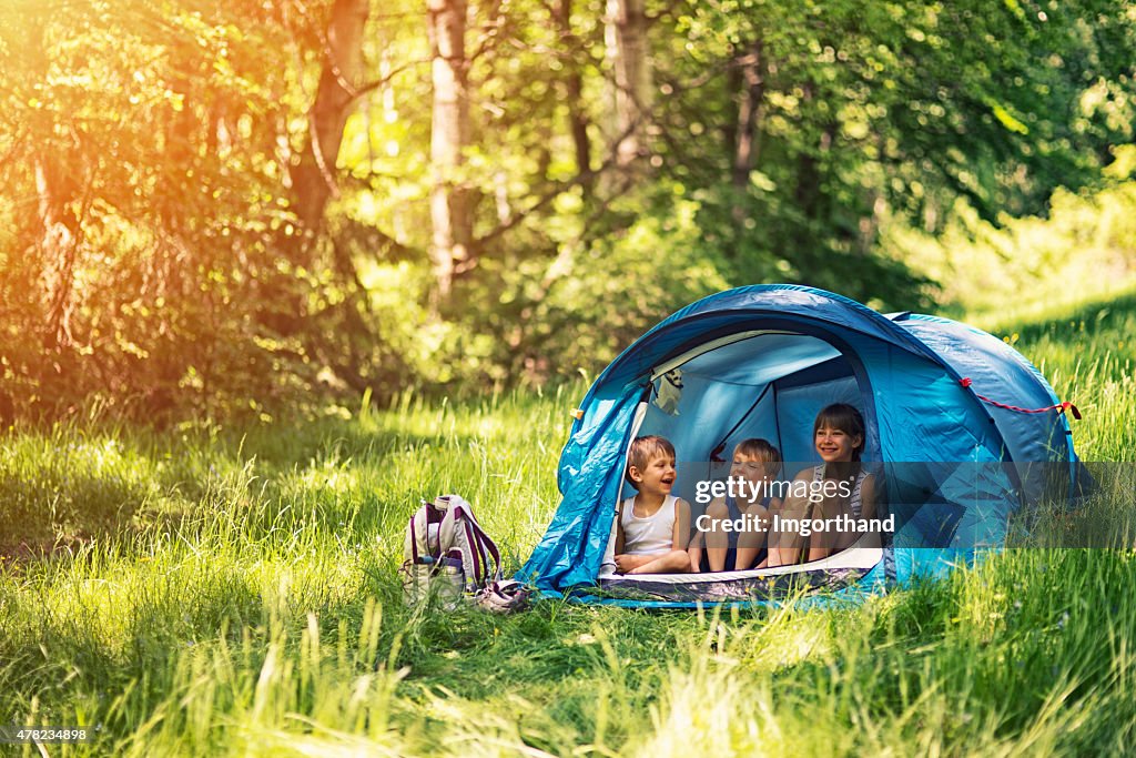 Hiker kids sitting in tent in the forest