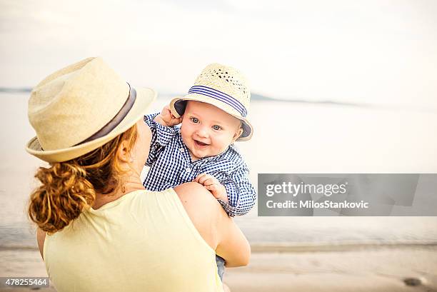 mom with baby on the beach - baby sommer stock pictures, royalty-free photos & images