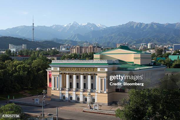 The Tien Shan mountains sit beyond the opera house in Almaty, Kazakhstan, on Tuesday, June 23, 2015. Kazakhstan completed its negotiations to become...