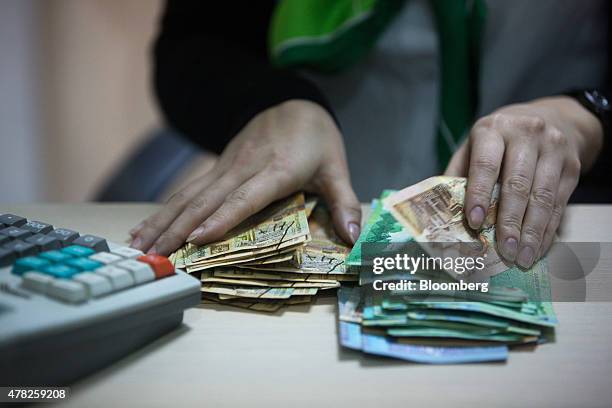 An employee counts tenge currency banknotes inside an OAO Sberbank bank branch in Almaty, Kazakhstan, on Tuesday, June 23, 2015. Kazakhstan completed...