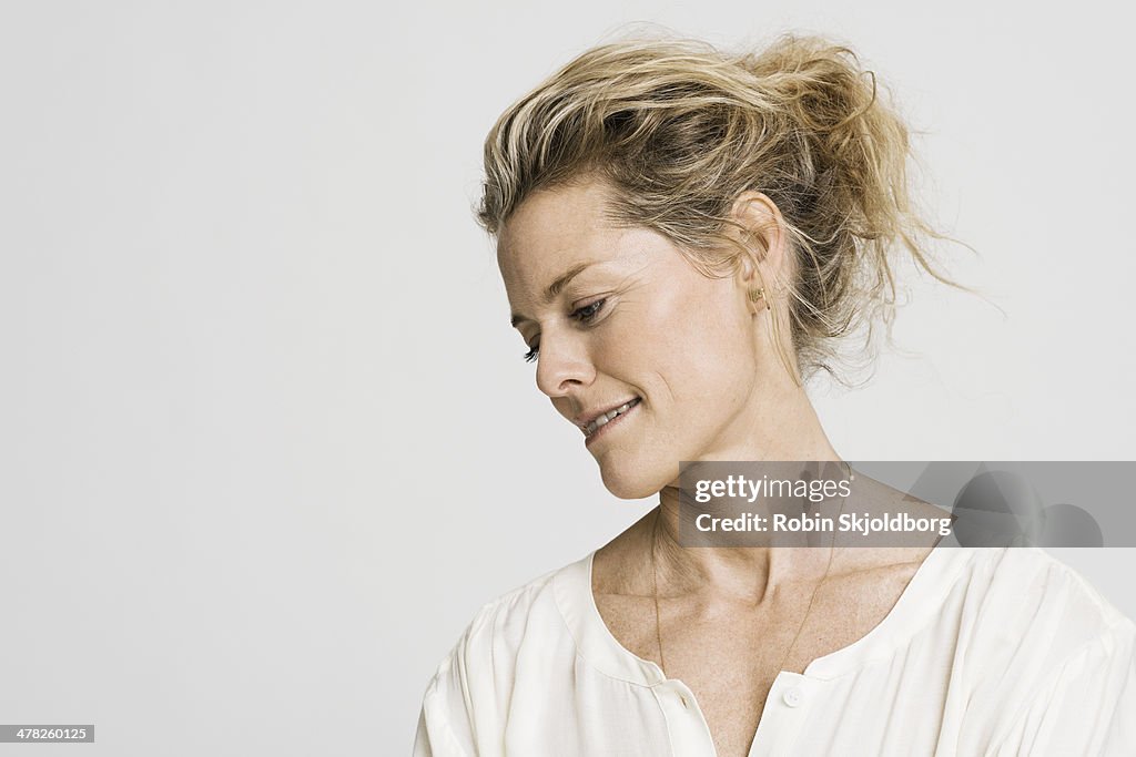 Mature woman in white shirt looking down