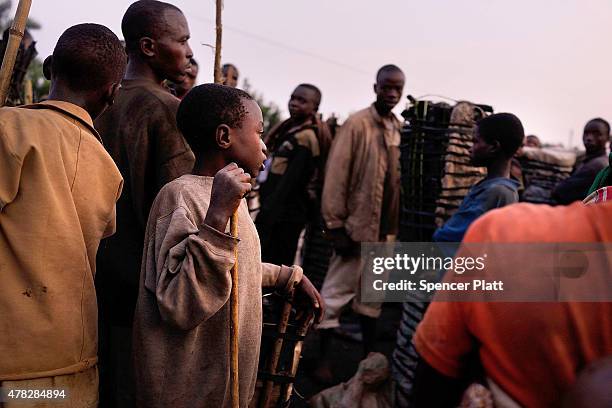 Charcoal workers of a variety of ages wait to sell their loads on June 24, 2015 in Kabezi, Burundi. The men and women often walk most of the night...