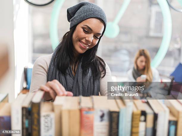 young smiling woman choosing a book in library. - choosing a book stock pictures, royalty-free photos & images