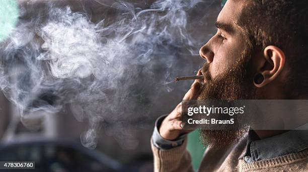 primo piano di un giovane hipster fumo di sigaretta. - spinello foto e immagini stock