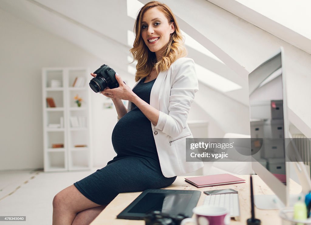 妊娠を持つビジネスウーマンデジタルカメラ、仕事で自分のオフィスにお問い合わせください。