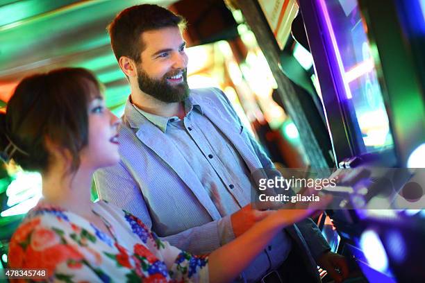 couple playing slots in casino. - gaming casino stock pictures, royalty-free photos & images