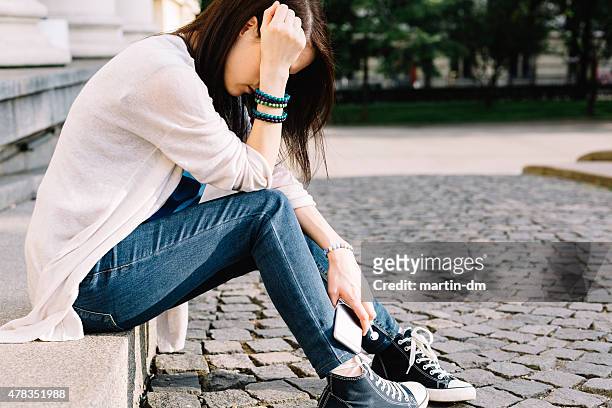 deprimida chica sesión en la calle - headache child fotografías e imágenes de stock
