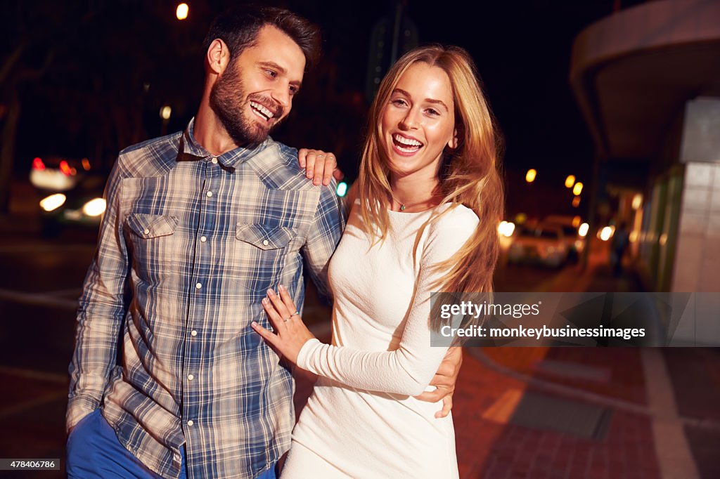 Couple walking through town together at night
