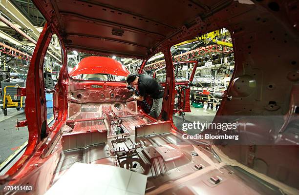 An employee works inside a new Nissan Leaf automobile as it travels along the production line at Nissan Motor Co.'s vehicle assembly plant in...