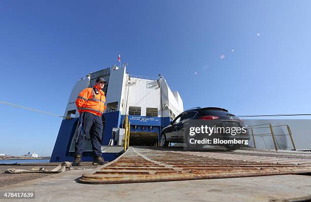 An employee watches as a new Infiniti SUV automobile, manufactured by Nissan Motor Co., is driven on to the City of Rotterdam export vessel at the...